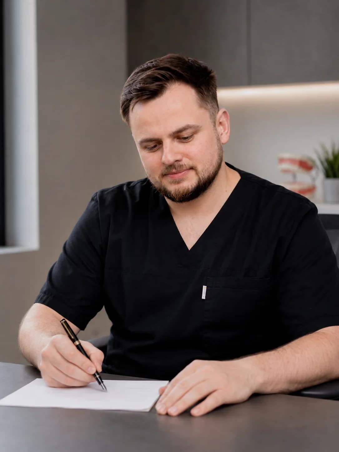 Lek. dent. Wojciech Kresta podczas pracy z dokumentacją leczenia w gabinecie stomatologicznym.